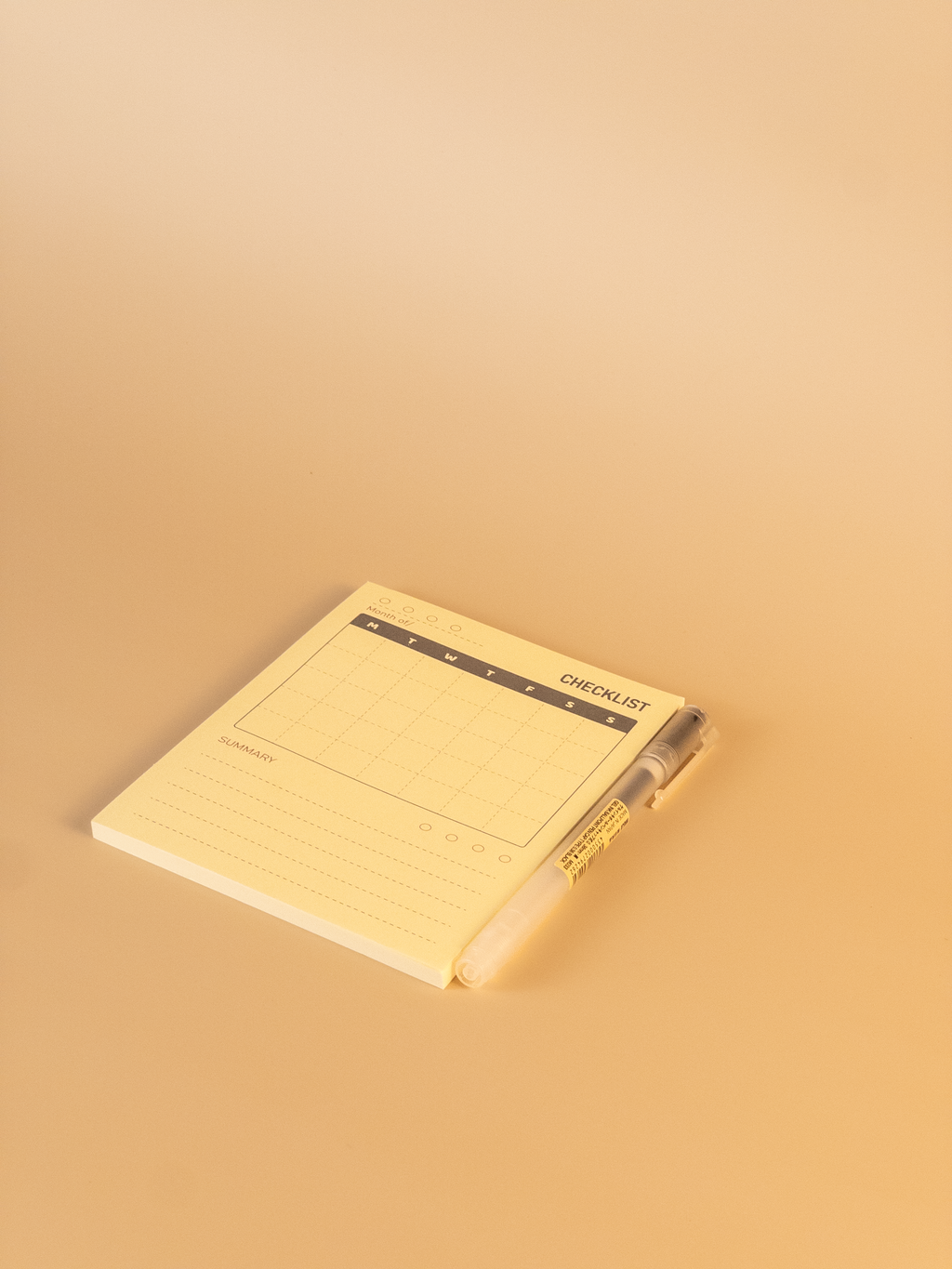 Yellow notepad with a pen on a beige background