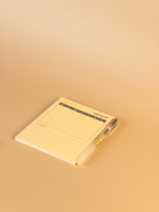 Yellow notepad with a pen on a beige background