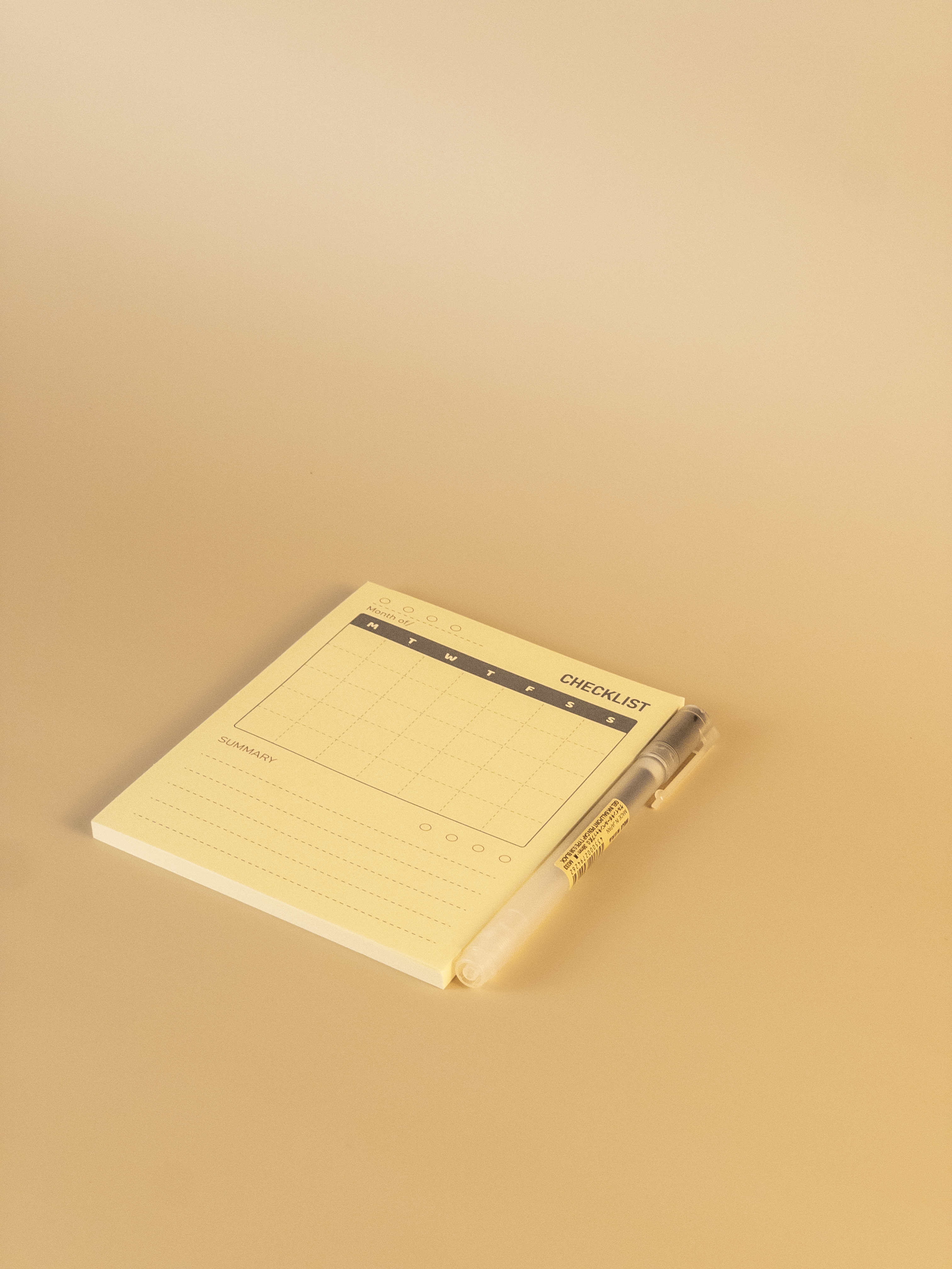 Yellow notepad with a pen on a beige background