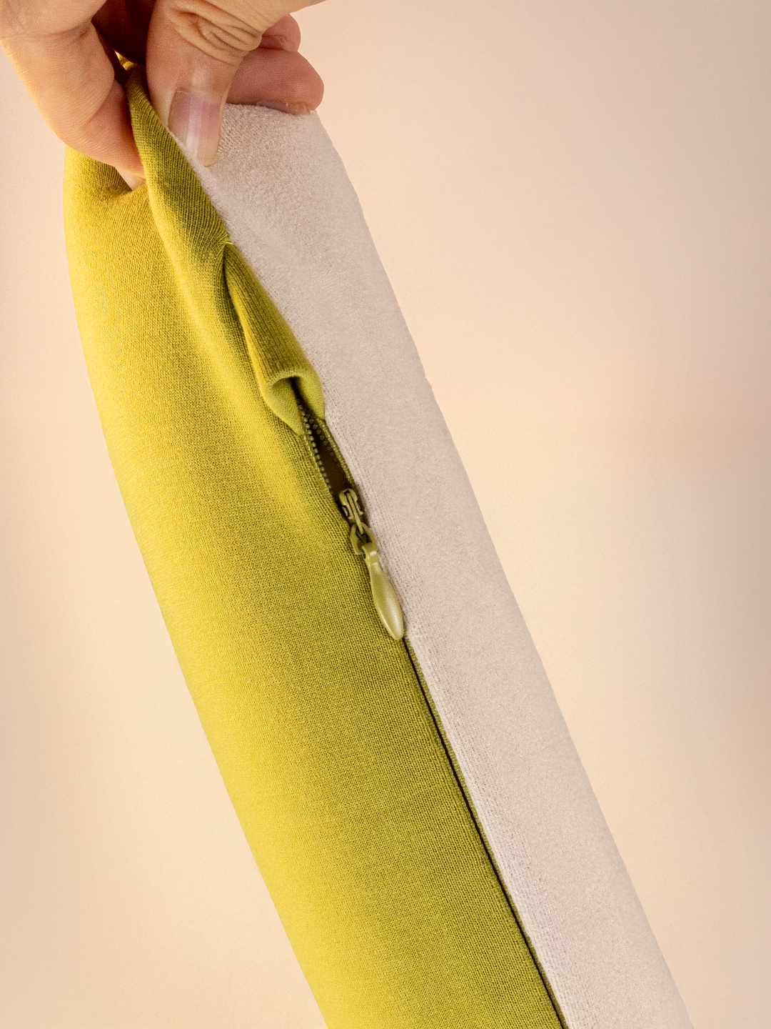 Green fabric with a zipper being pulled on a beige background