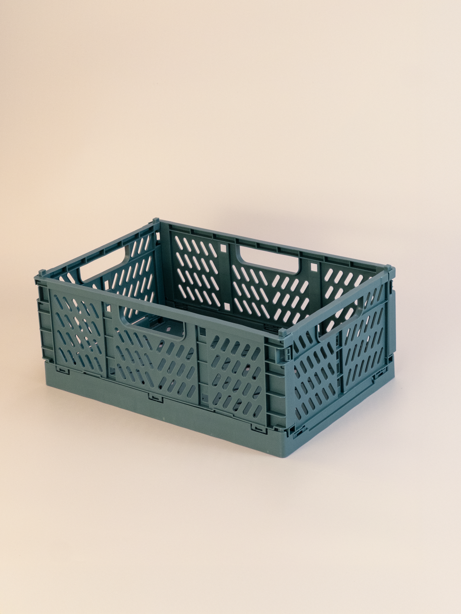 Green plastic storage container crate on a beige background
