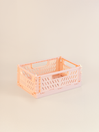 Small pink plastic crate on a beige background