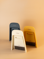 Three cleaning brushes in black, white, and yellow on a beige background