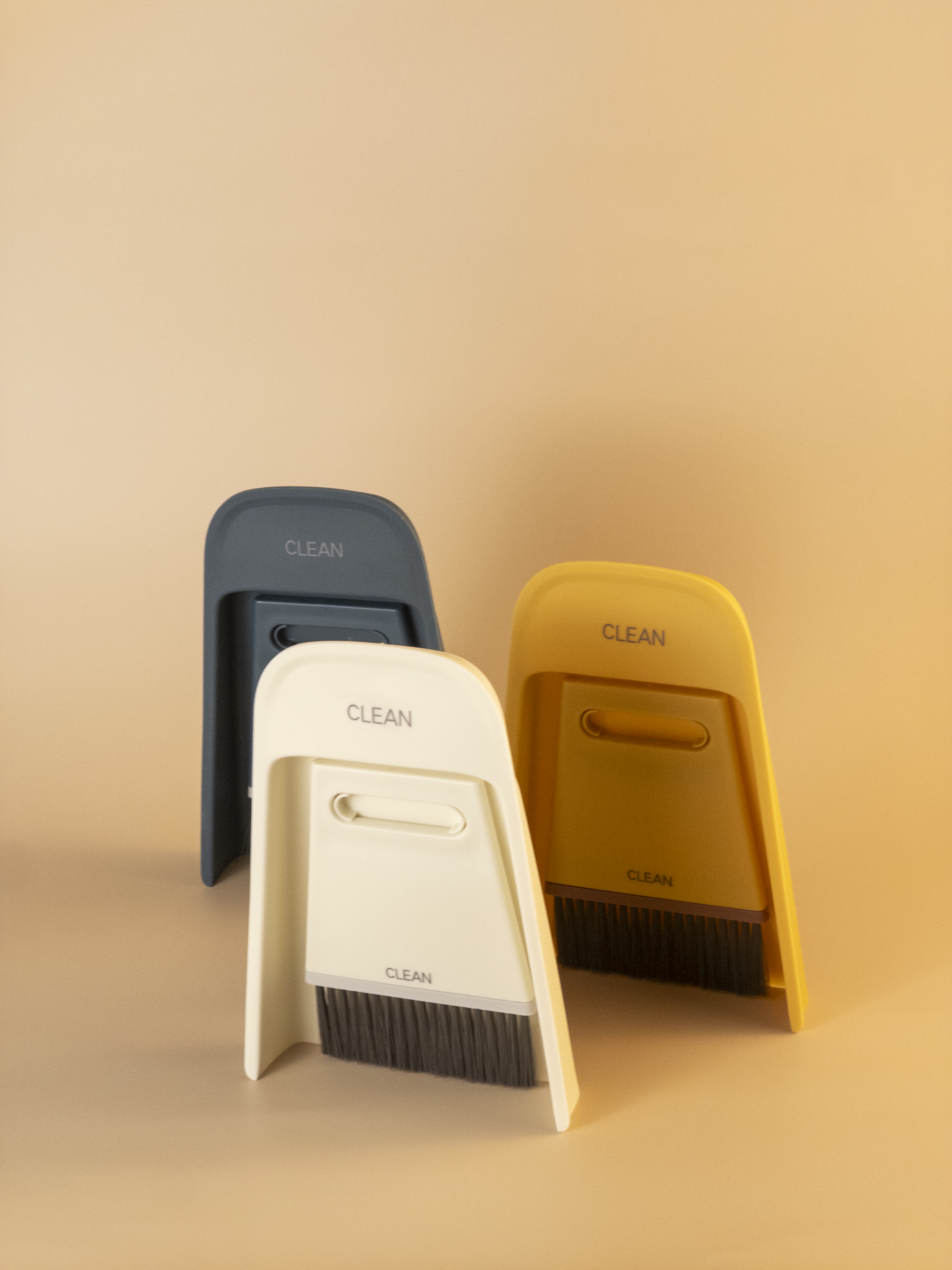 Three cleaning brushes in black, white, and yellow on a beige background