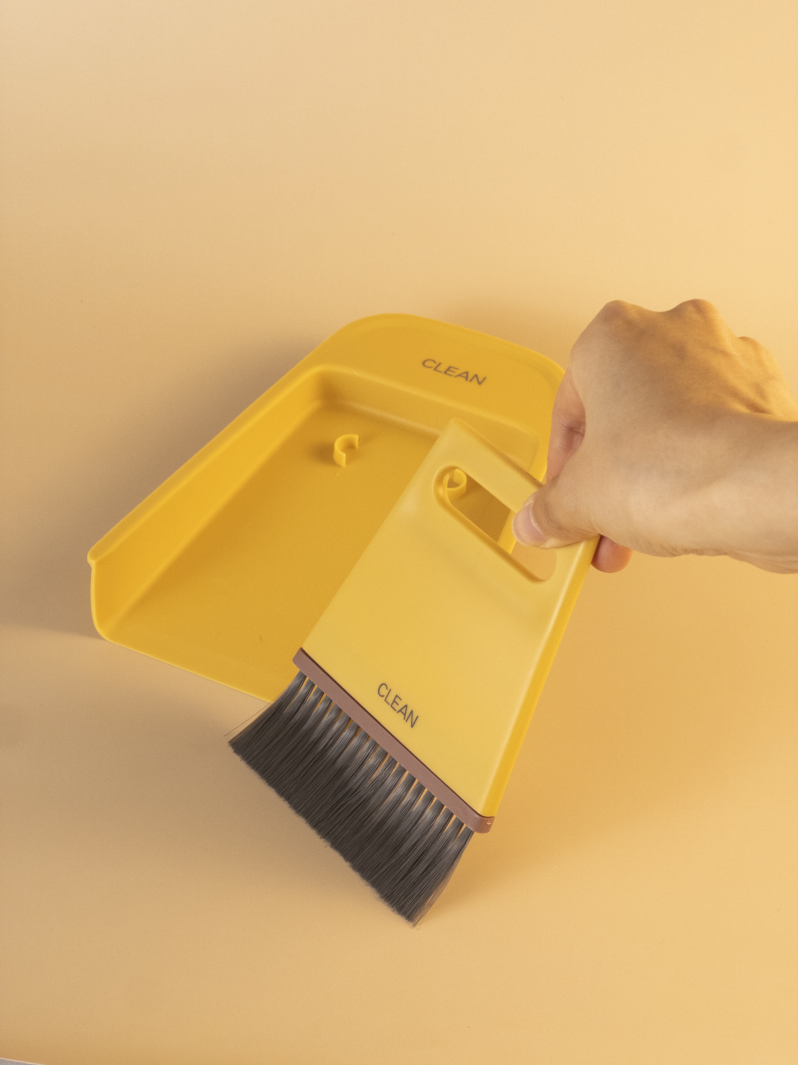 Yellow cleaning brush with bristles and a handle, labeled 'Clean', on a yellow background.