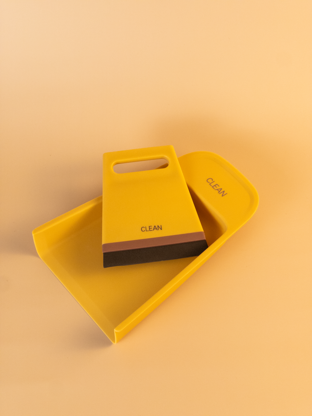 Yellow dustpan and brush set with 'Clean' text on a beige background