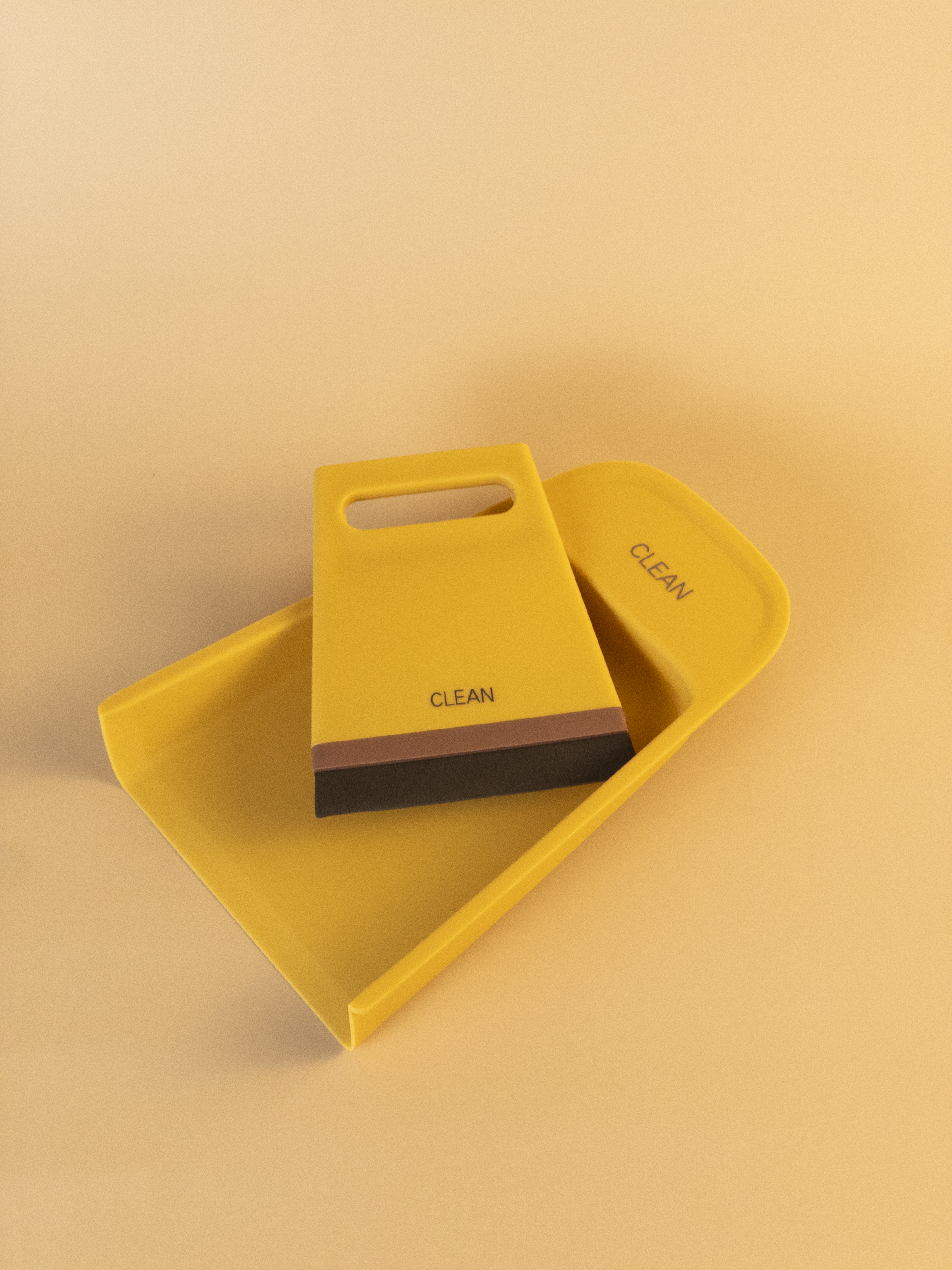Yellow dustpan and brush set with 'Clean' text on a beige background