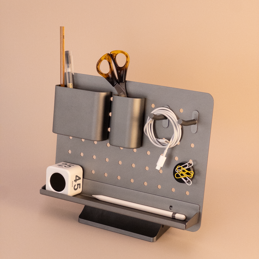 Gray pegboard with various office supplies on a beige background