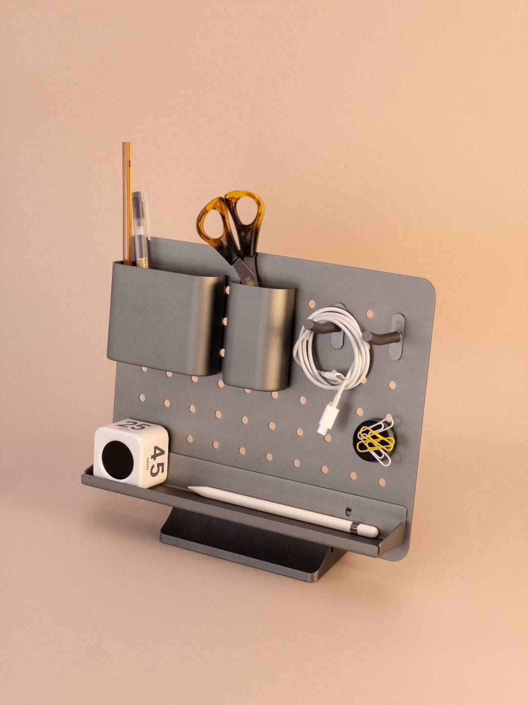 Gray pegboard with various office supplies on a beige background