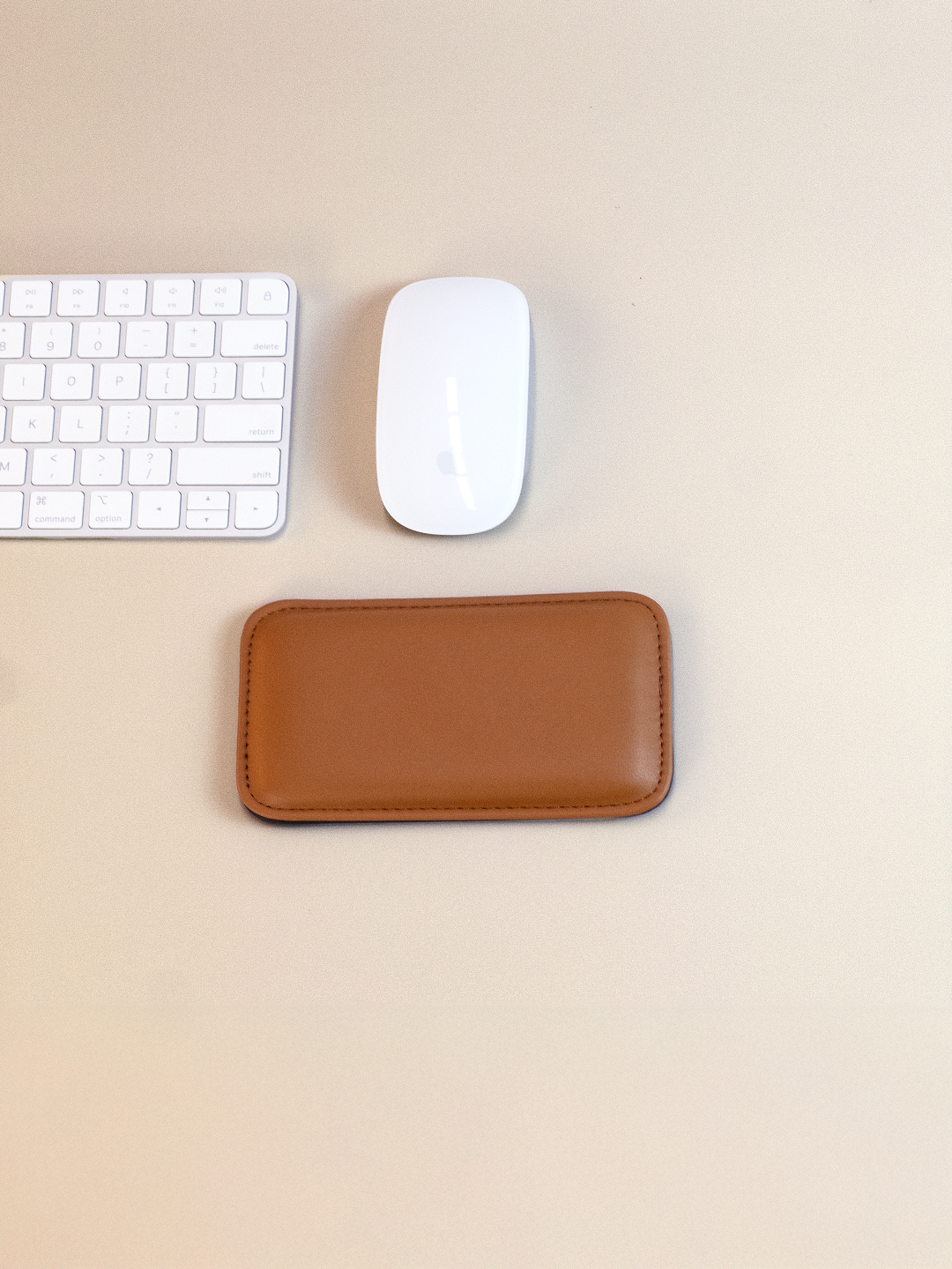 Brown leather mouse pad with a white keyboard and mouse on a beige background