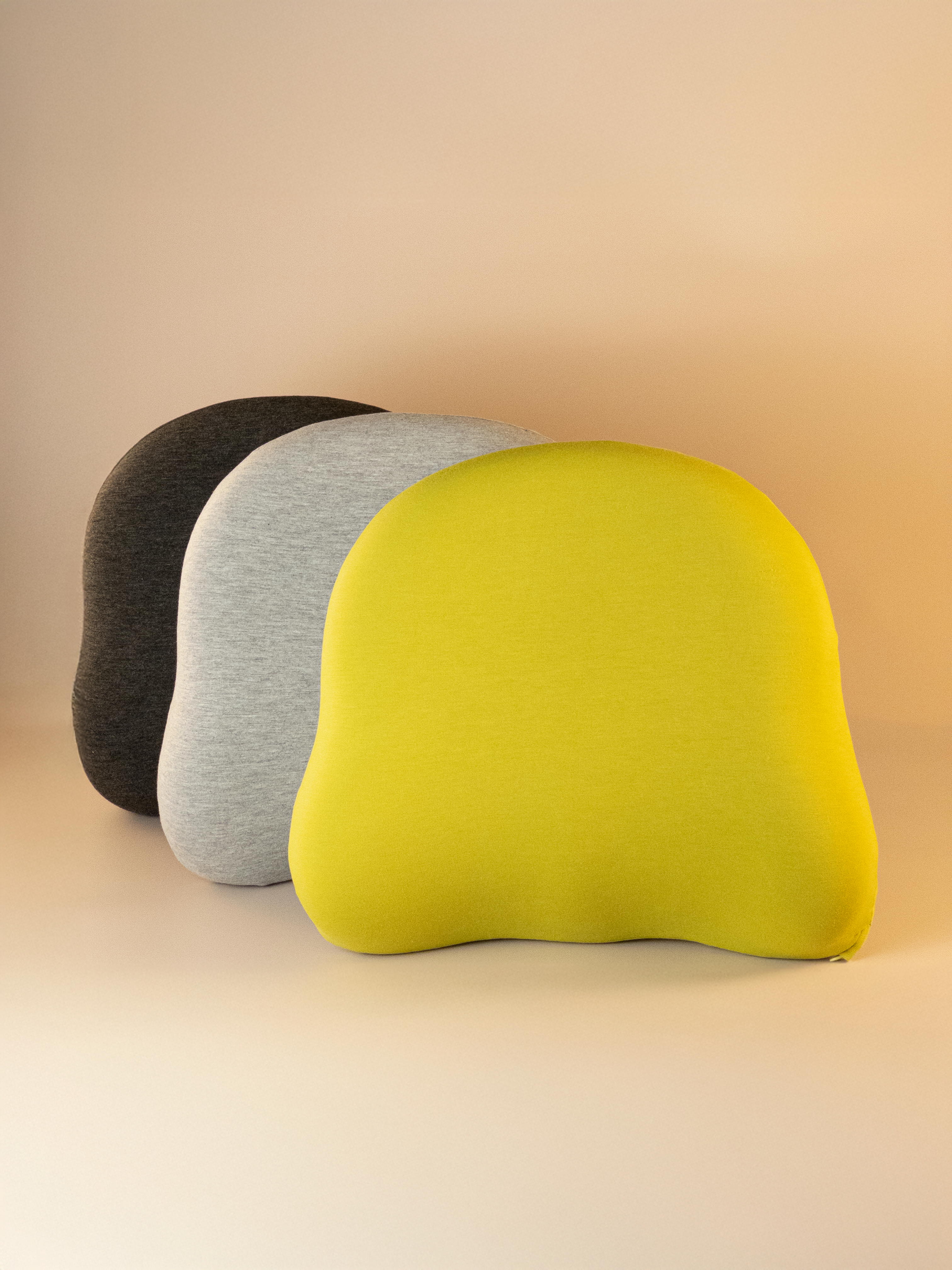 Three ergonomic back support cushions in black, gray, and green on a beige background