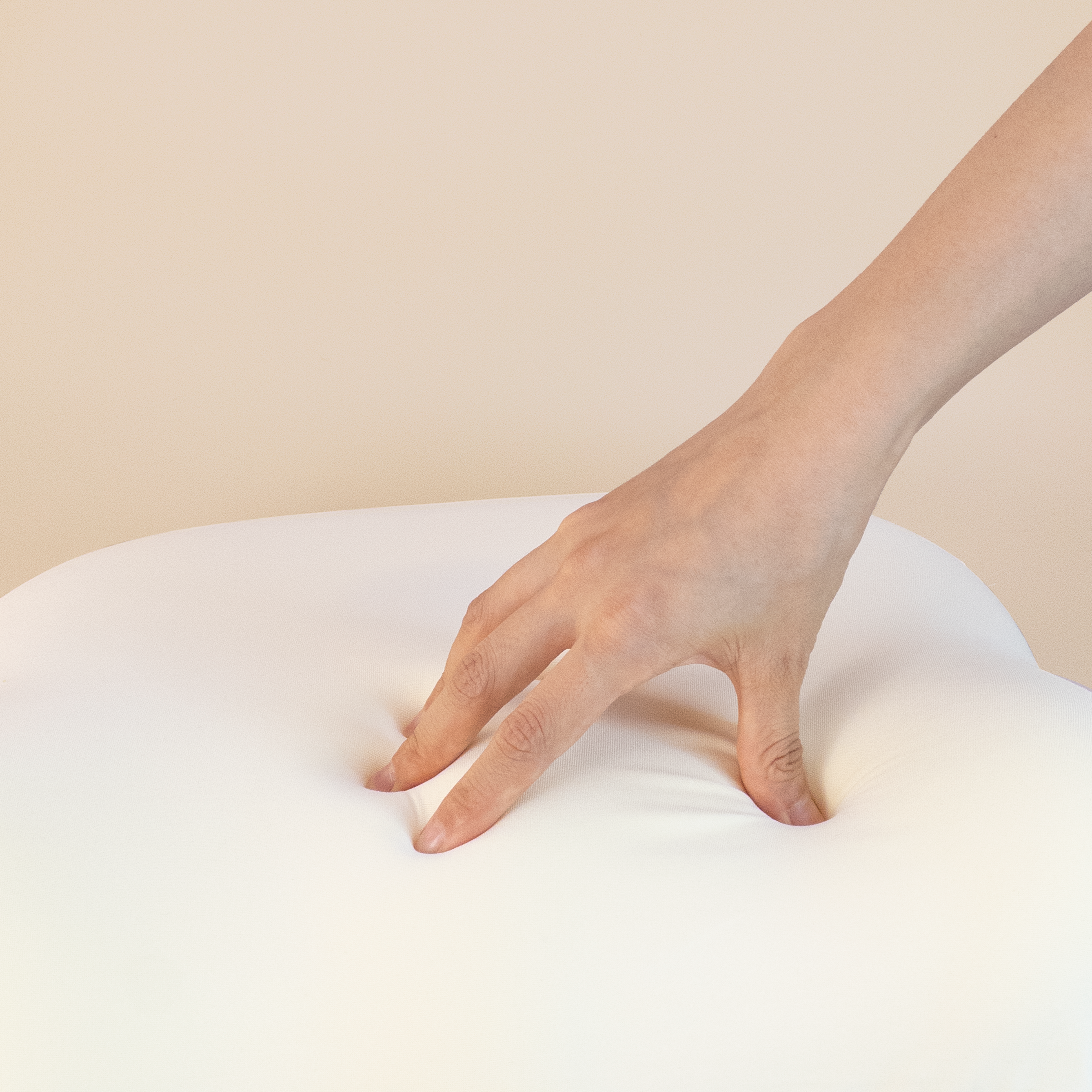 Close-up of a hand pressing into the memory foam cushion core, showing its soft rebound and strong support.