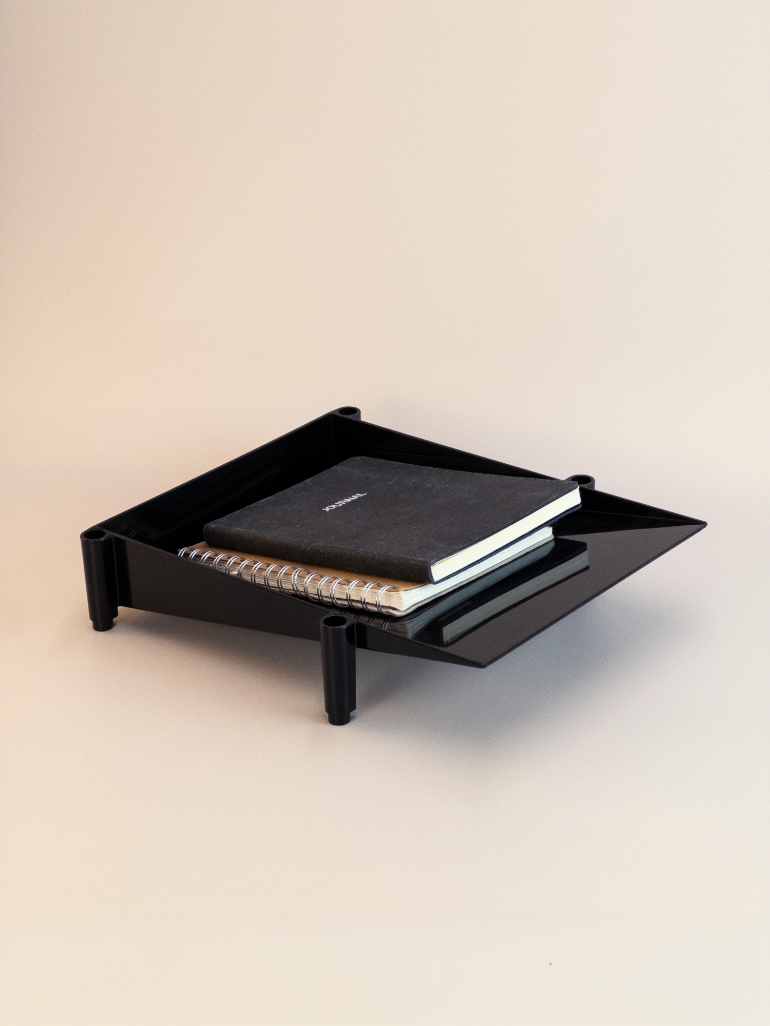 Black tray with a notebook on a beige background