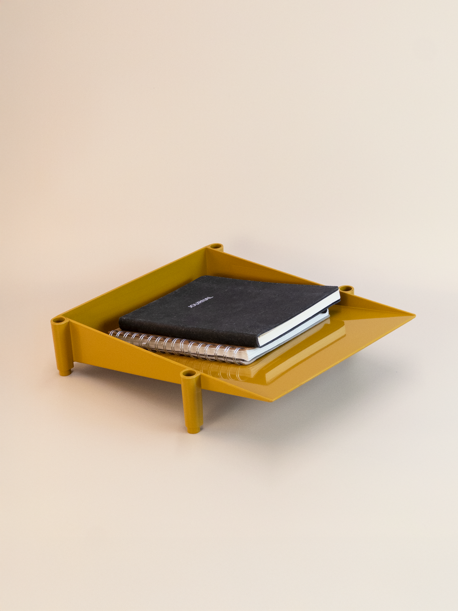 Yellow  tray with a notebook on a beige background