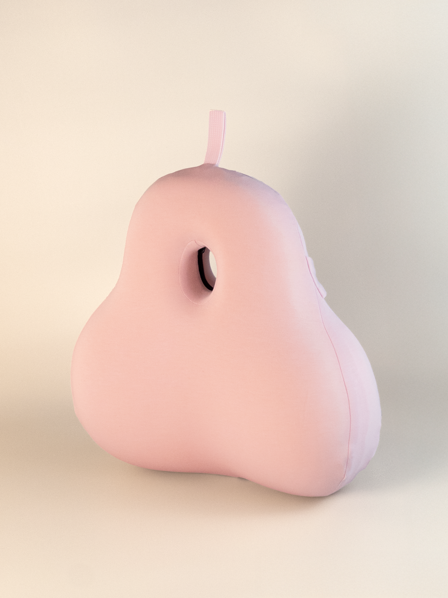 Pink pear-shaped lumbar cushion on a beige background