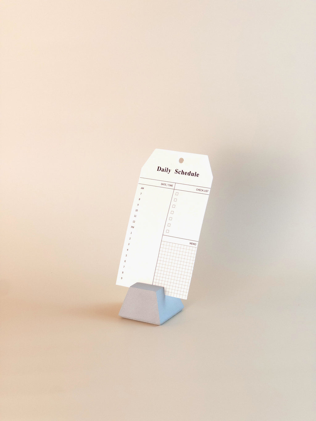 Concrete note holder displaying daily schedule planner card on desk