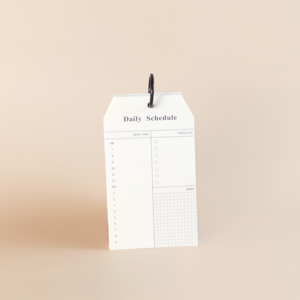 White daily schedule notepad with black text on a beige background