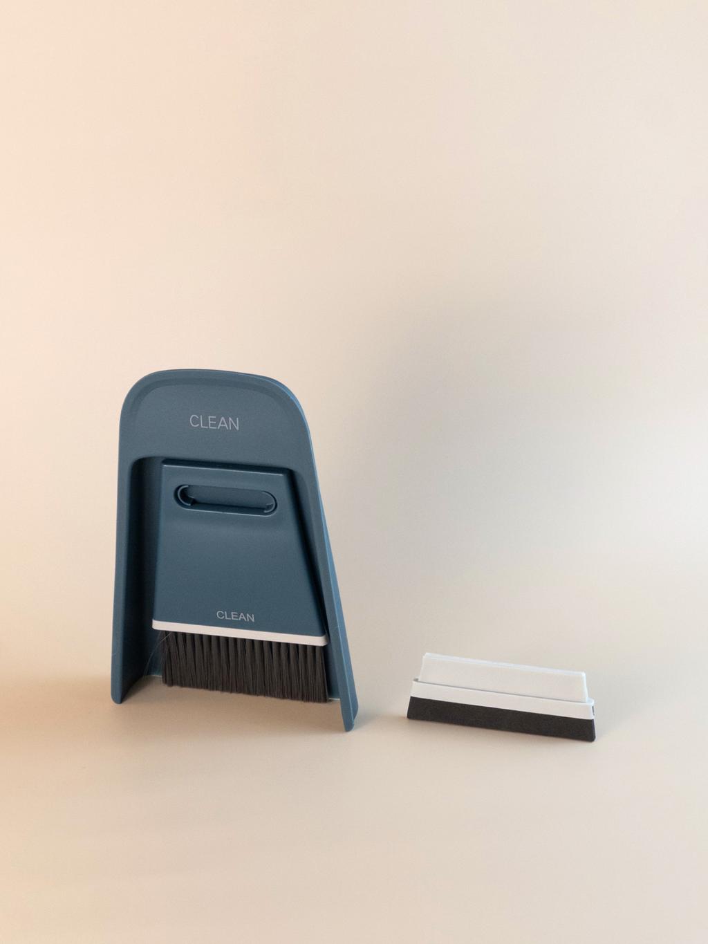 Navy blue desktop cleaning brush set, featuring soft bristles and a slim dustpan for workspace organisation.