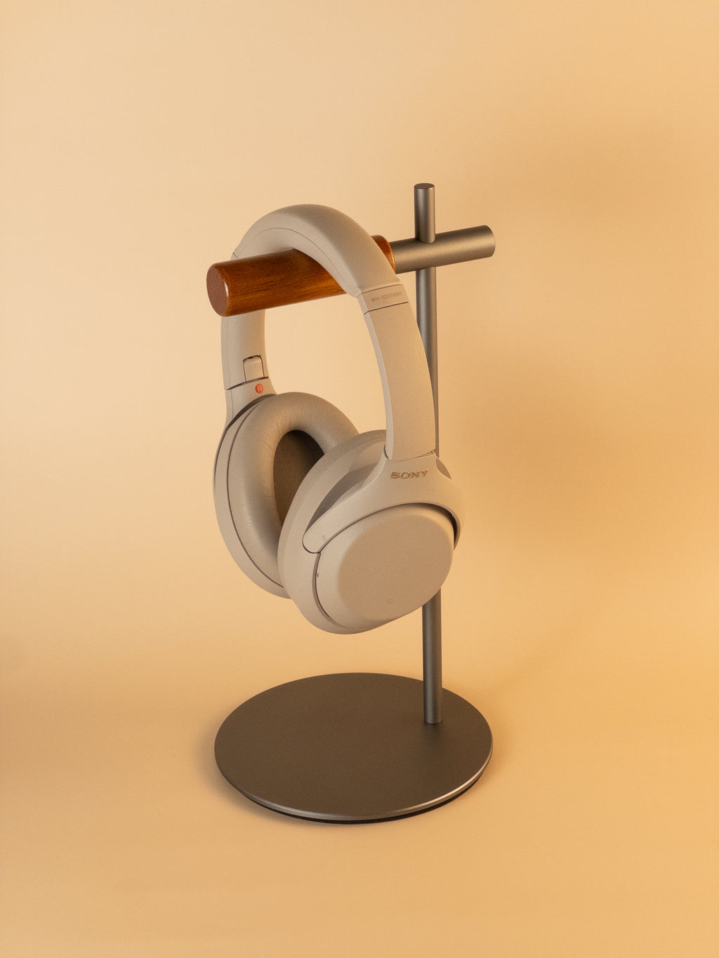 Grey aluminum headphone stand with wooden hanger displaying headphones