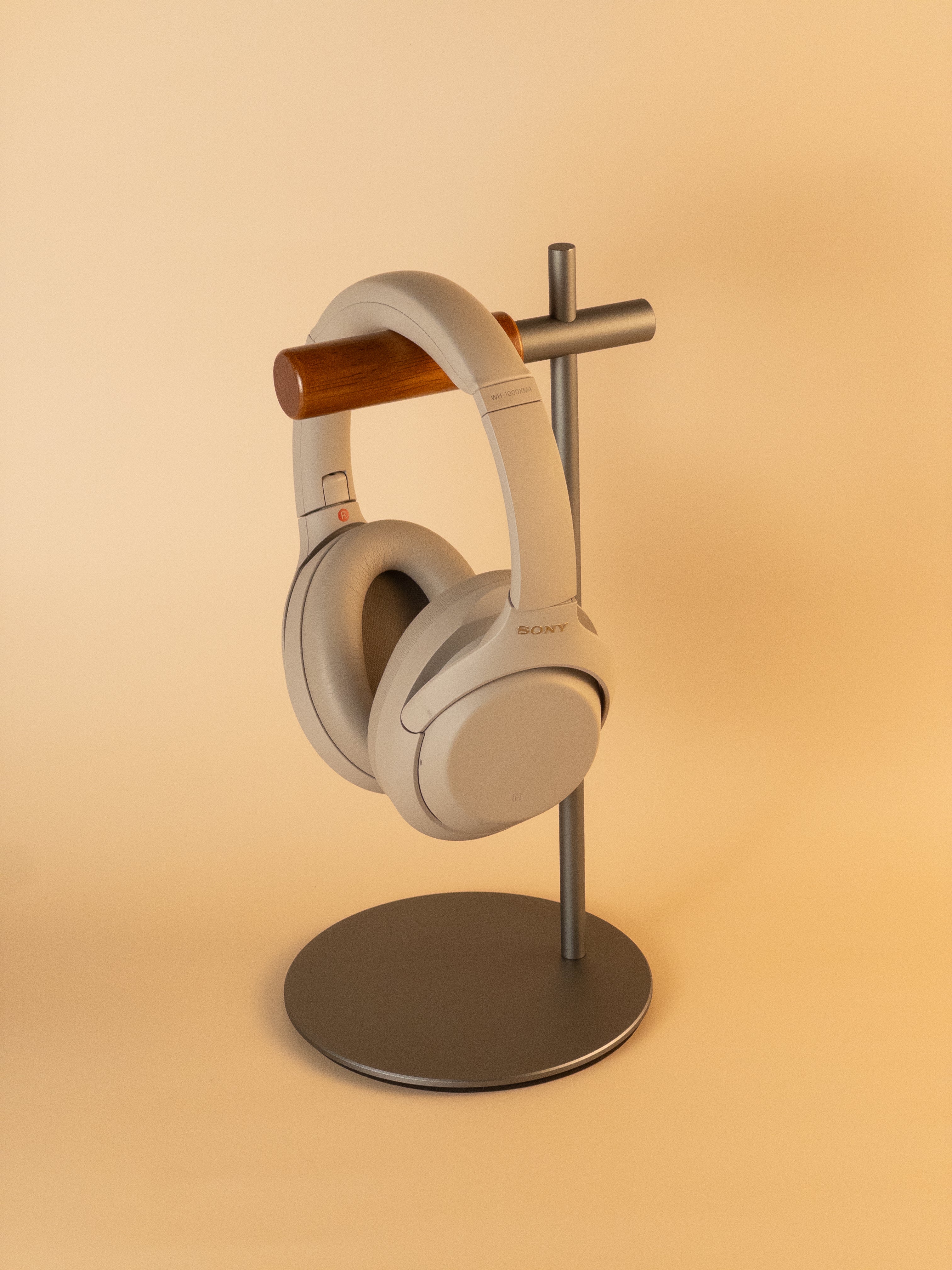 Grey aluminum headphone stand with wooden hanger displaying headphones