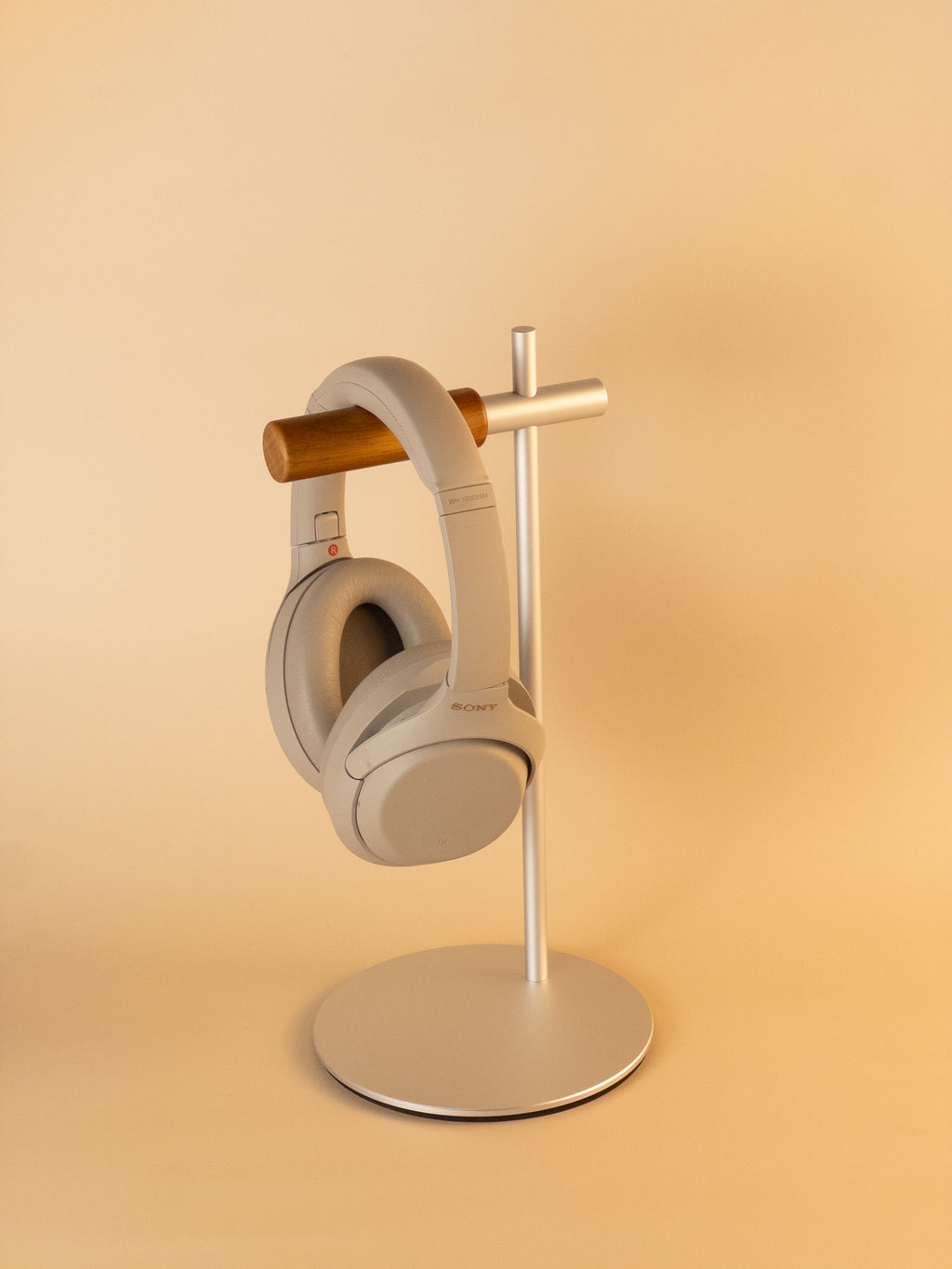 Silver aluminum headphone stand with wooden hanger holding over-ear headphones