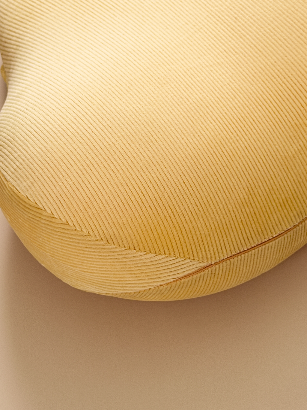 Close-up of a textured yellow cushion on a beige background