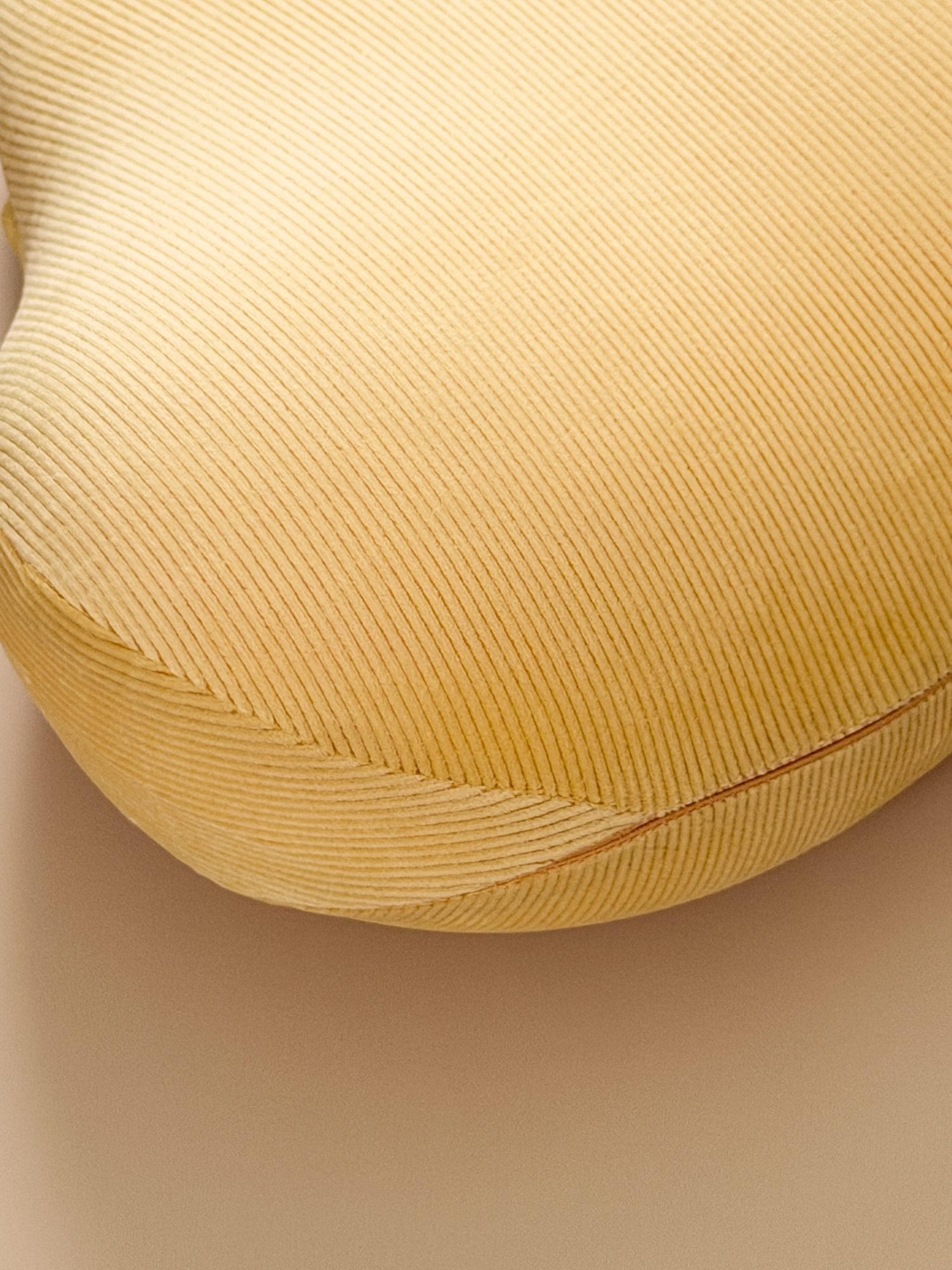 Close-up of a textured yellow cushion on a beige background