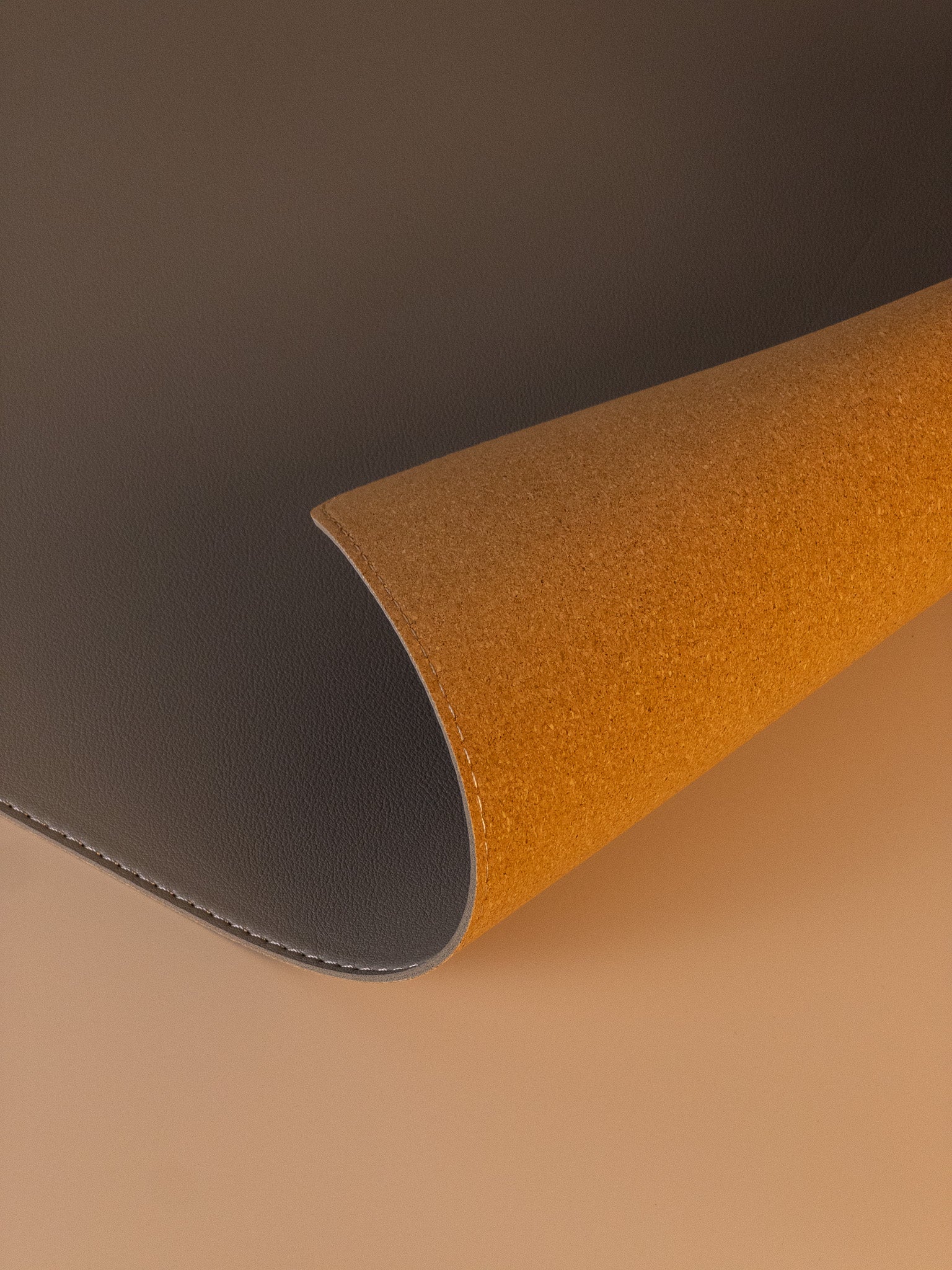 Close-up of slim leather desk mat showing natural cork backside, flexible and durable design