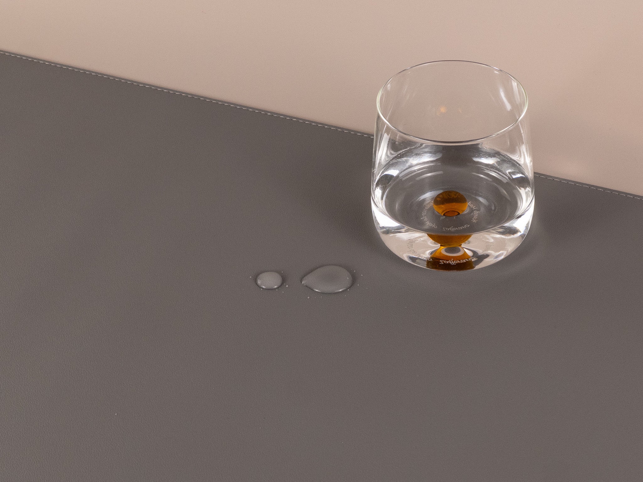 Slim grey leather desk mat with water droplets and glass cup, waterproof and easy to clean